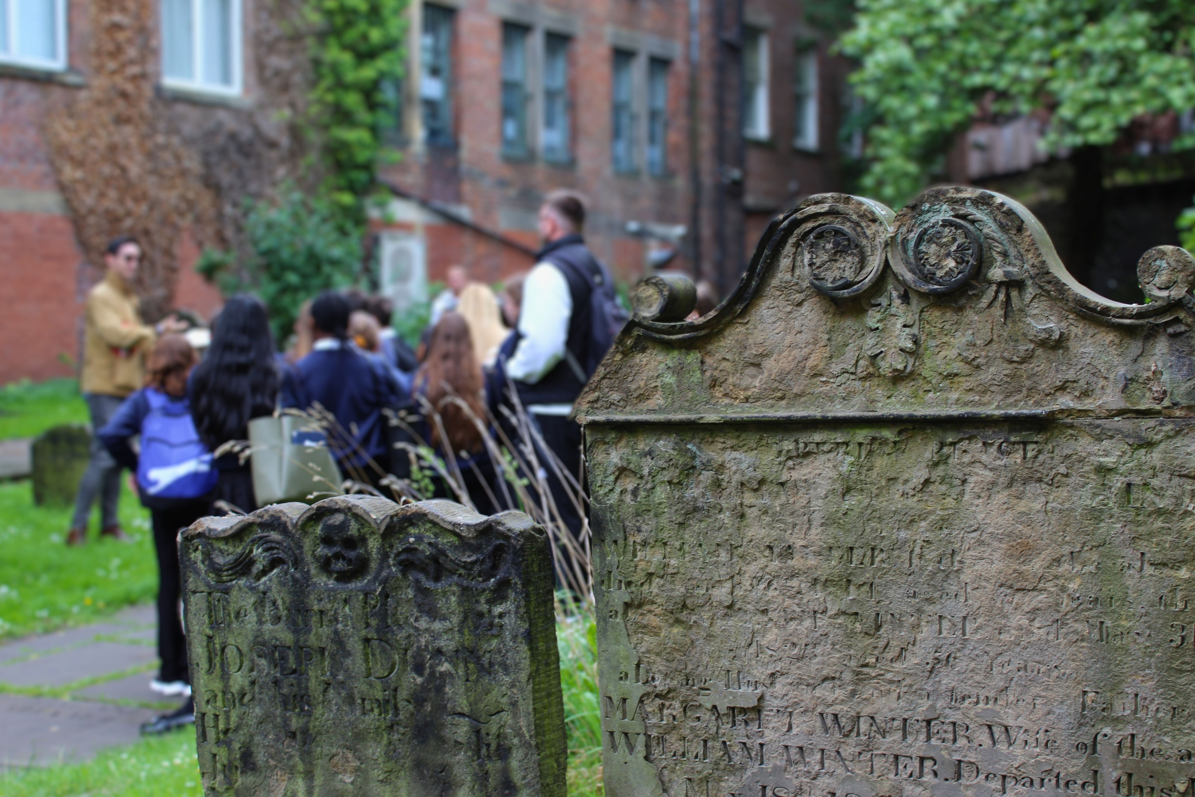Two gravestones with a group of students in the background