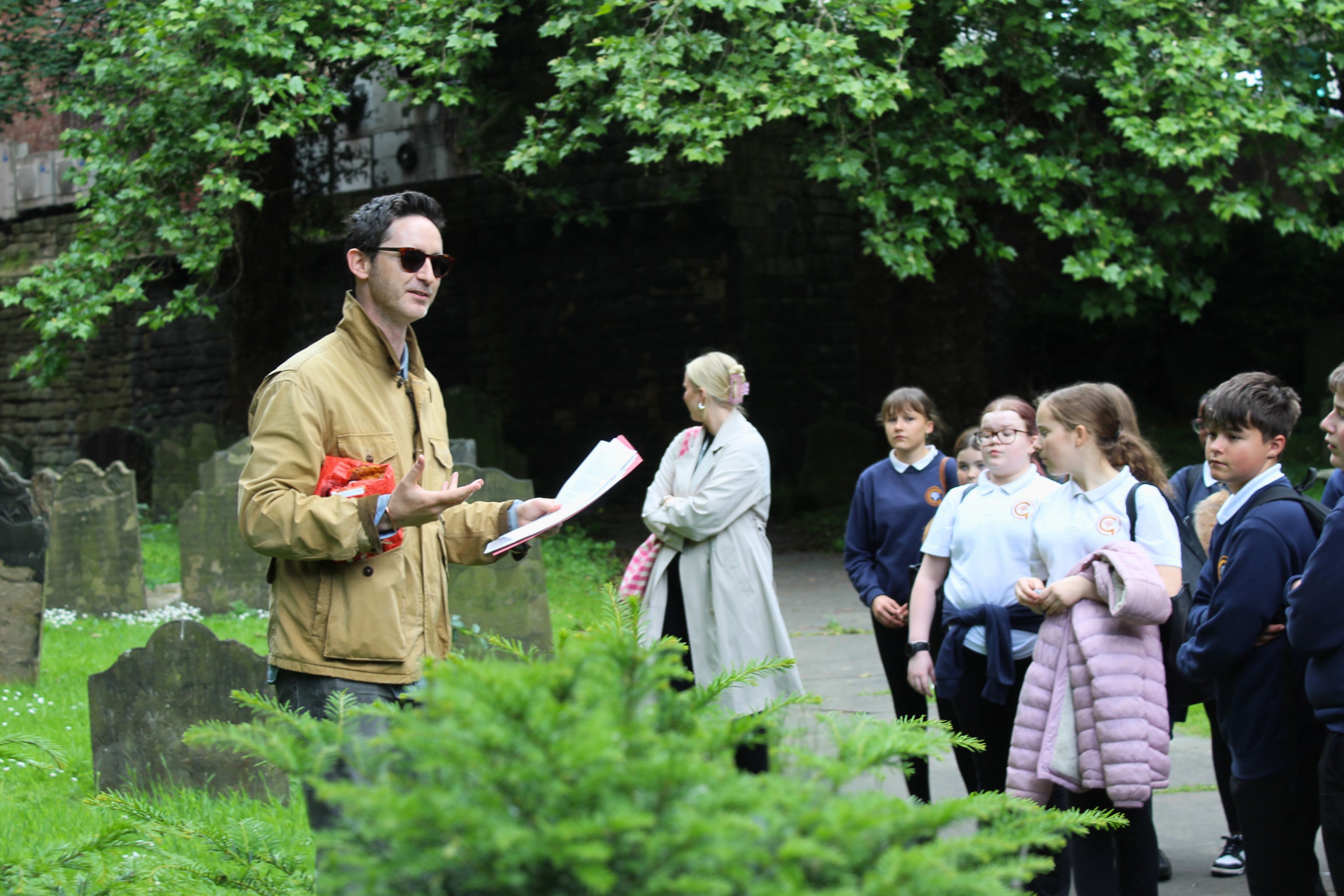 A historian talking to students in St Andrew's Churchyard