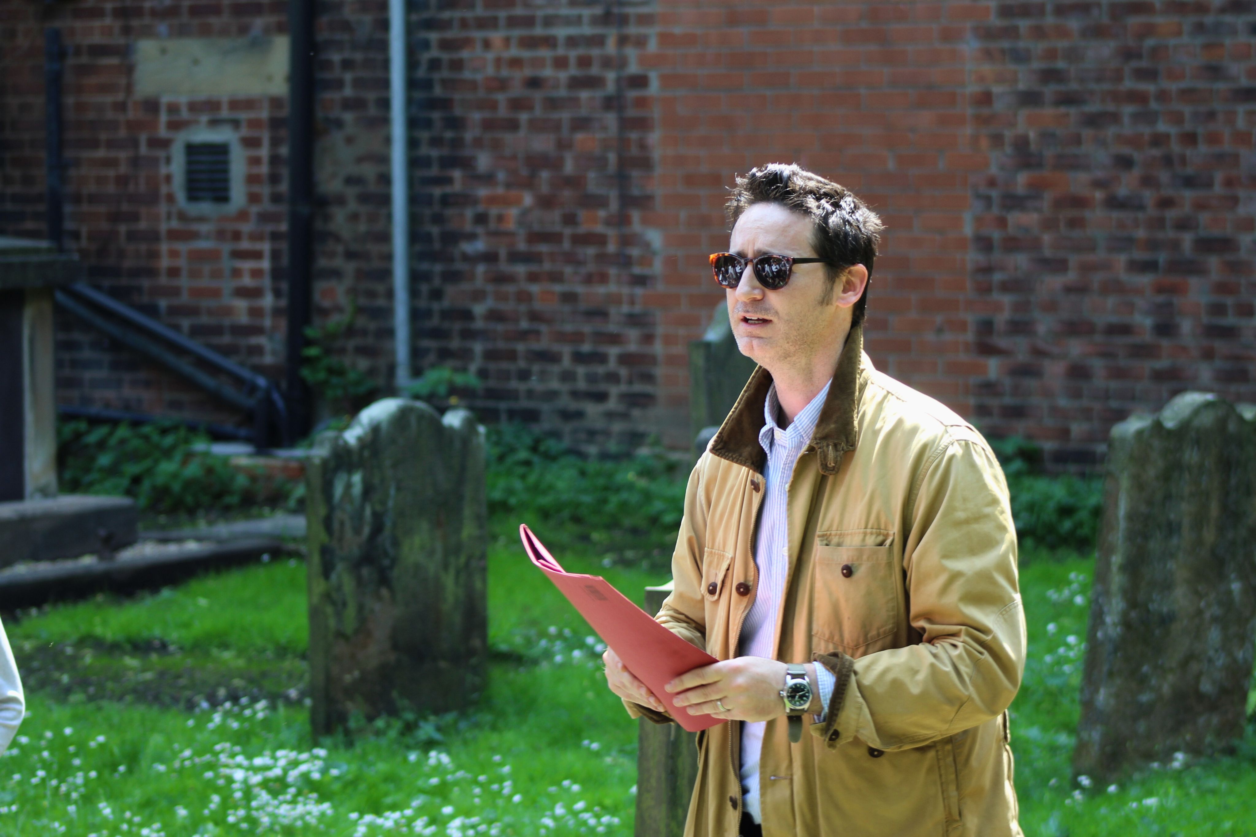 A historian holding a red folder speaking