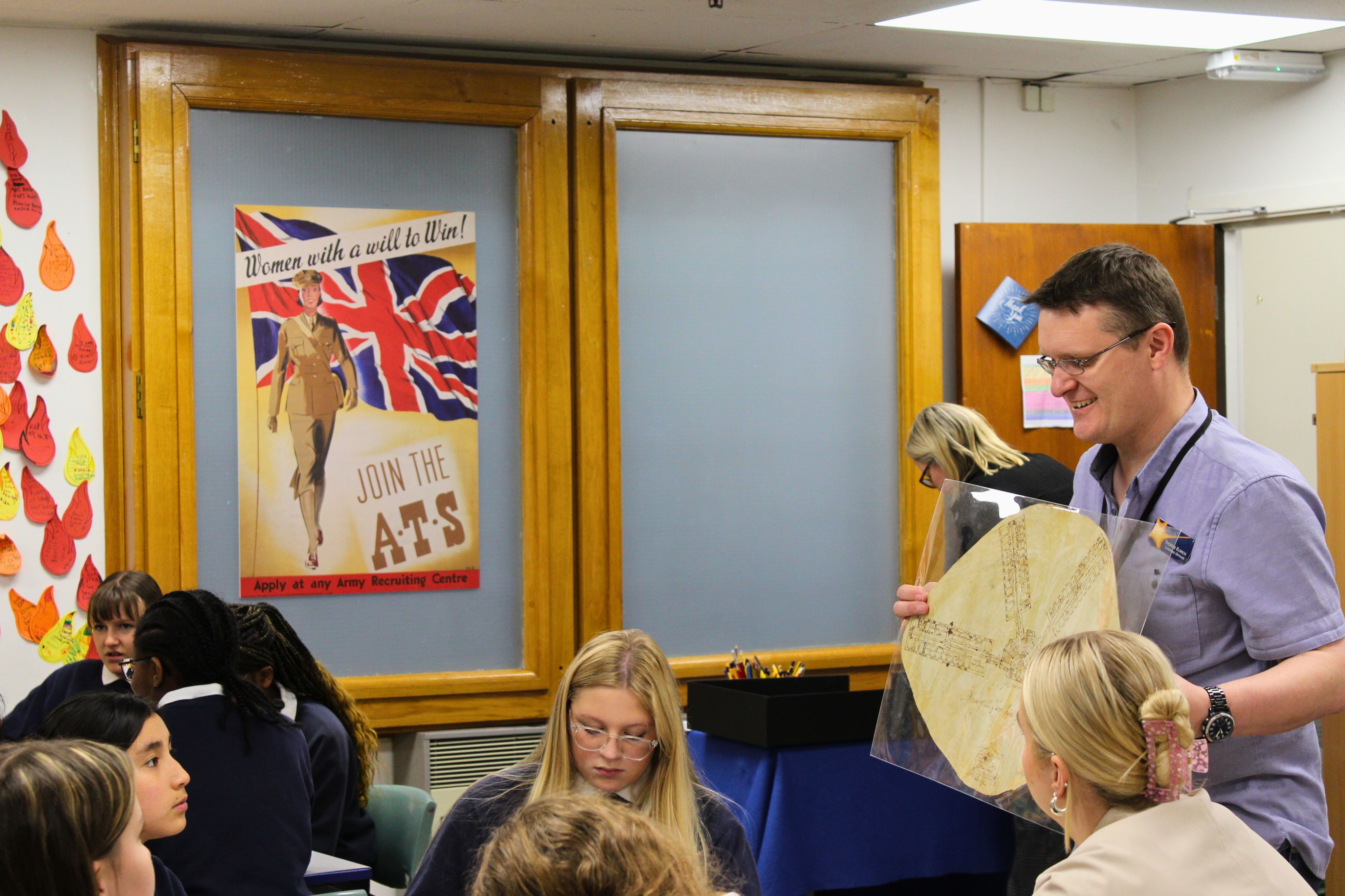 A person holding an archival drawing to a group of students