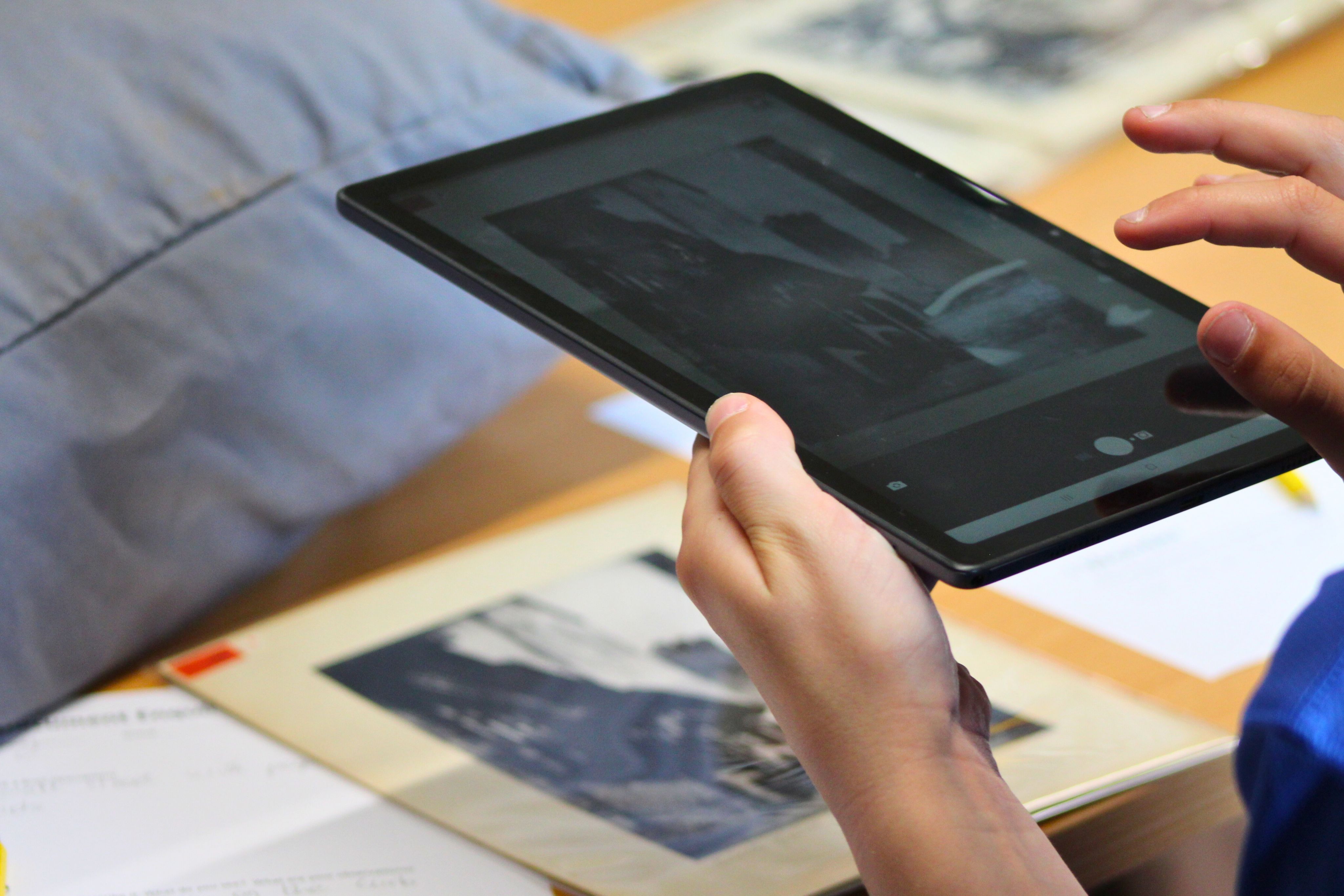 Hands holding a tablet taking a photo over a table