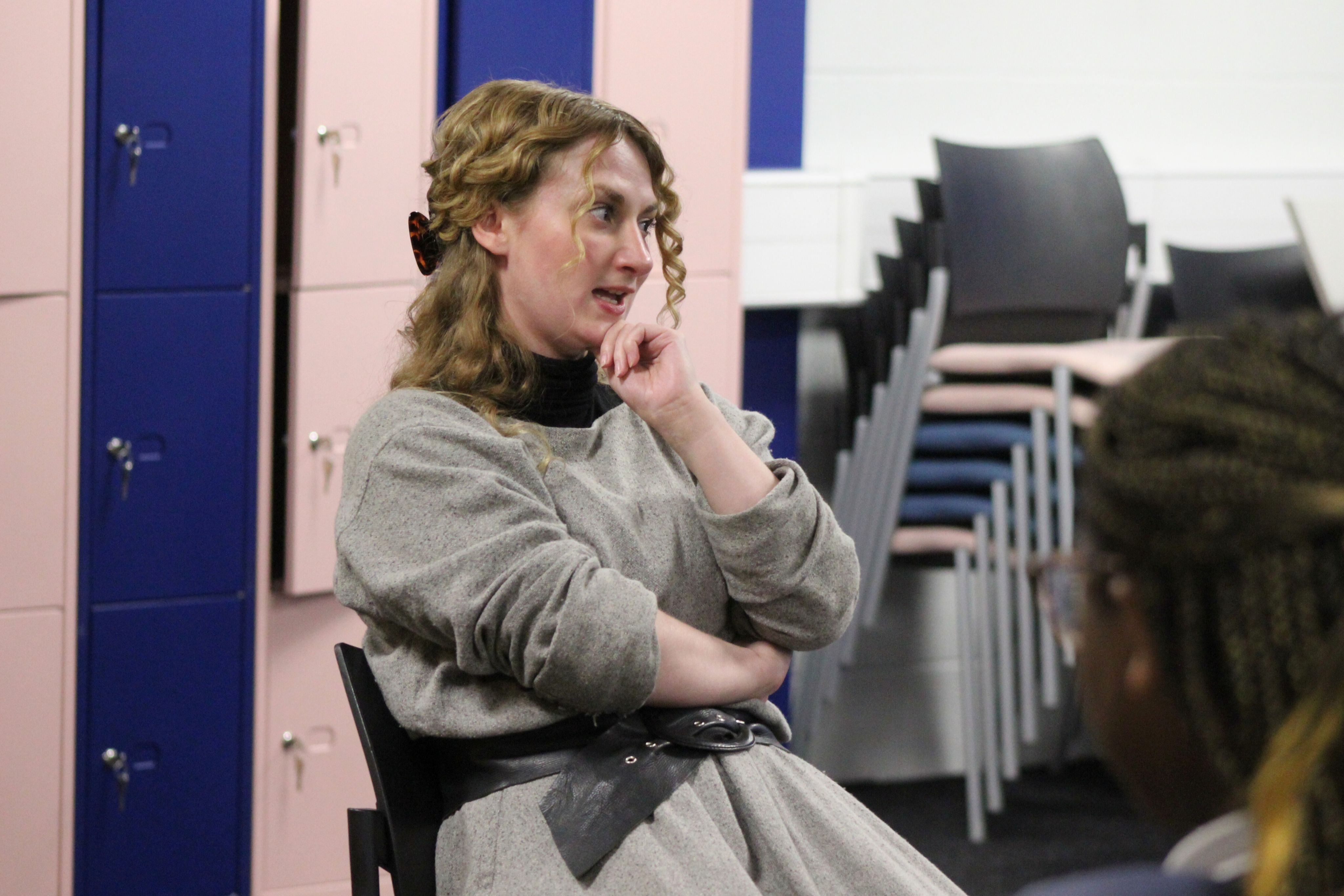 An actress dressed in grey prison costume talking to children