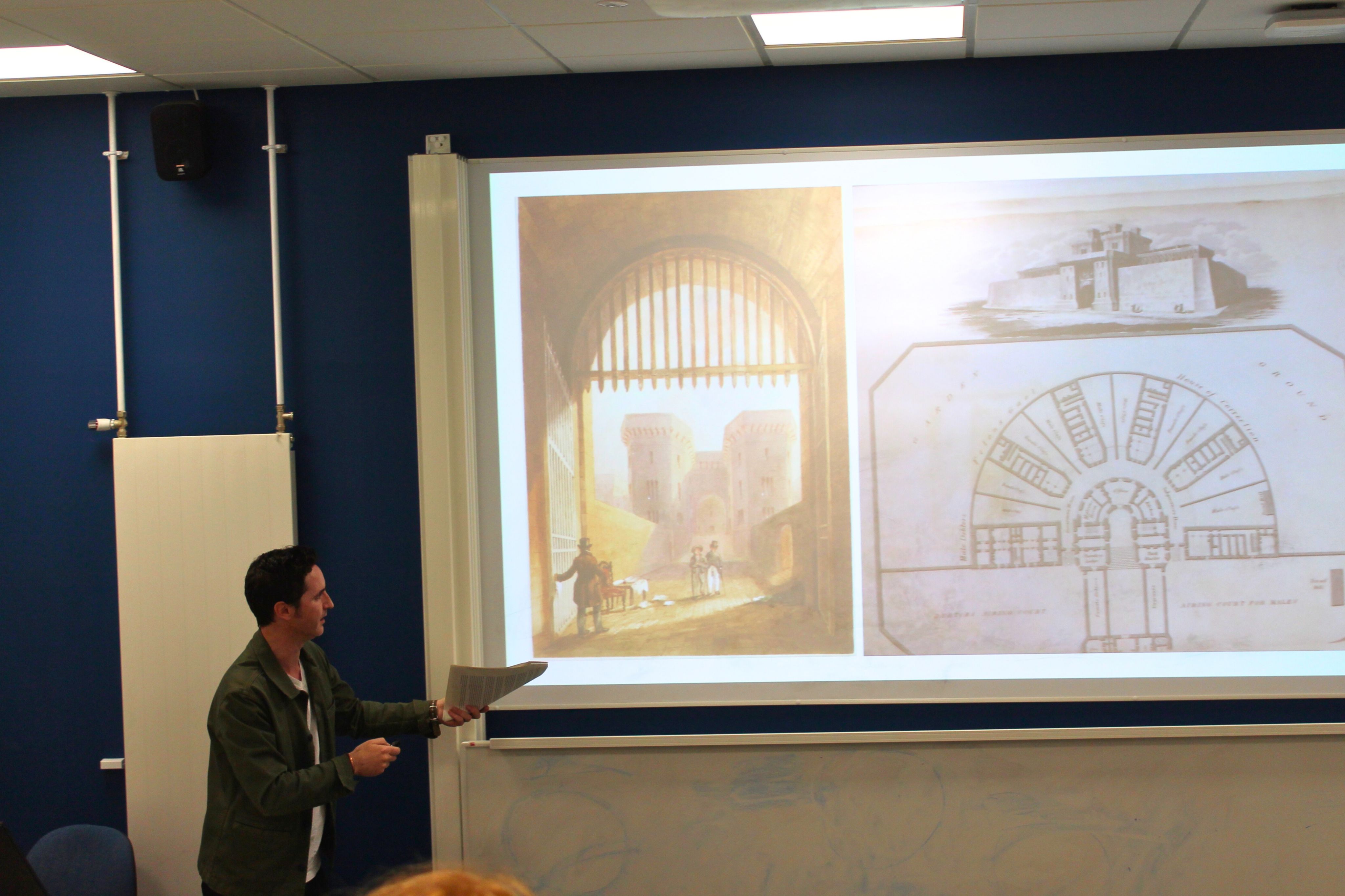 A lecturer standing in front of a screen 