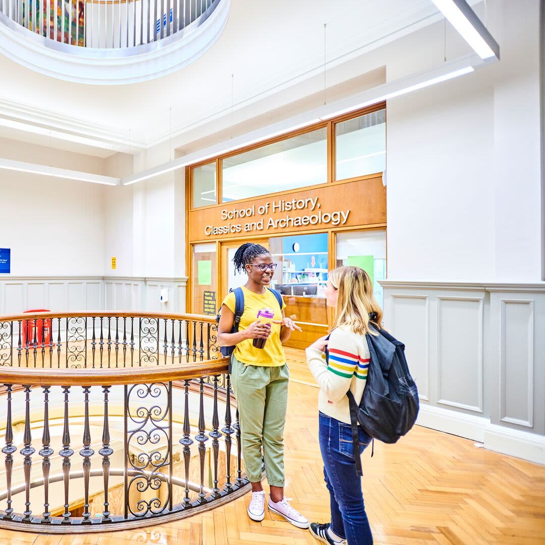 Two students stood talking in the School of History, Classics and Archaeology