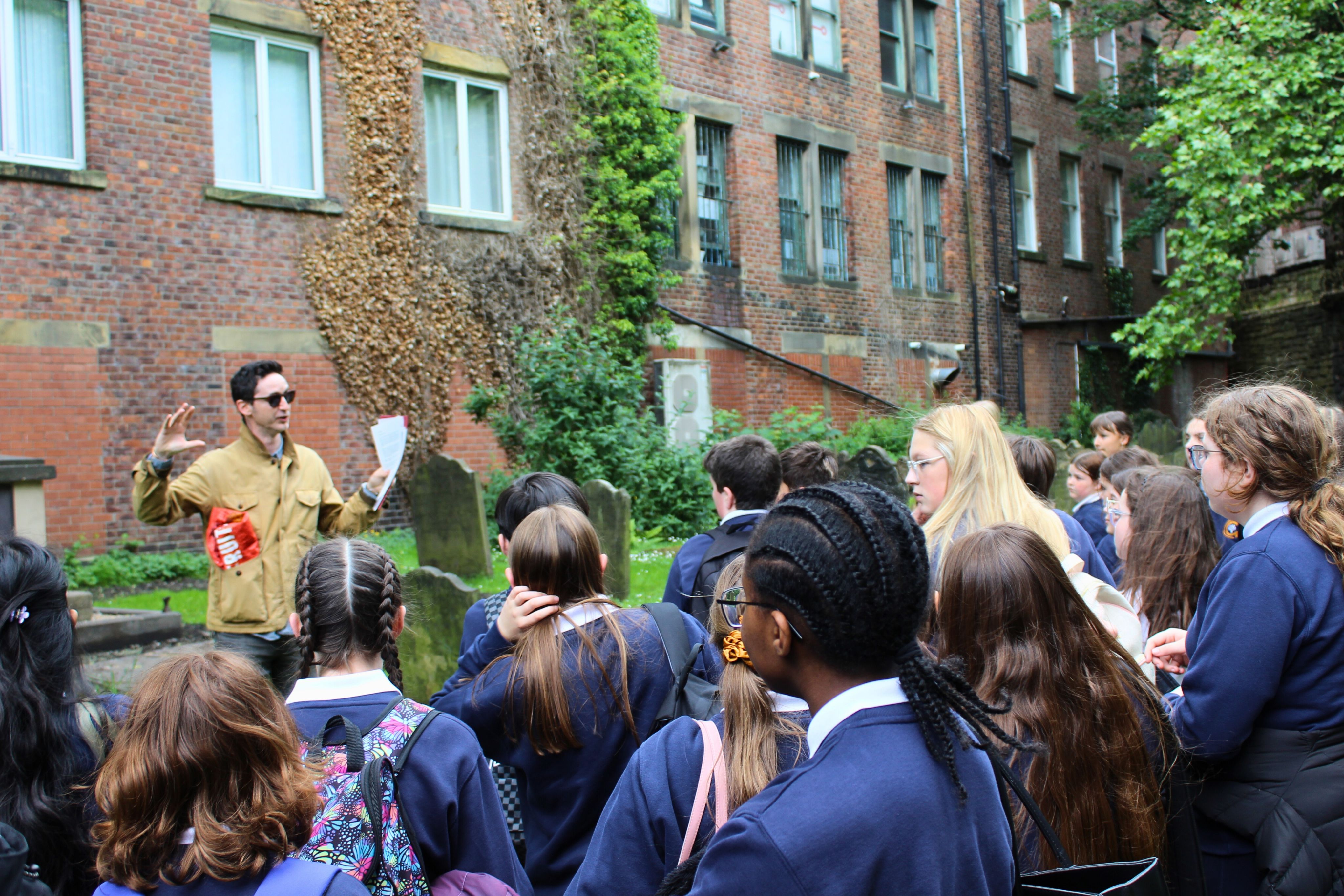 A historian and a group of students stood in a graveyard