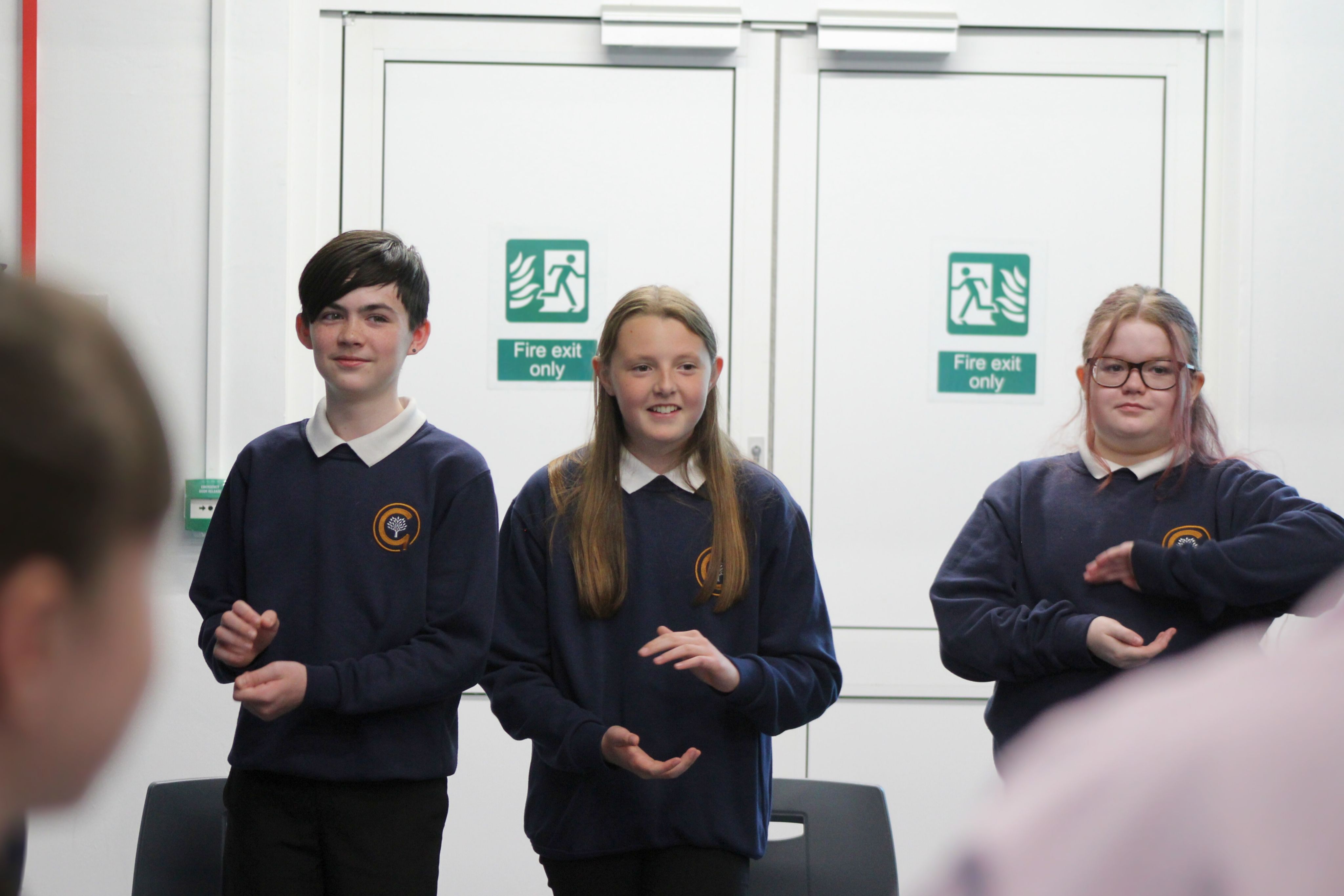 Three students stood with their hands in front of them during a drama activity