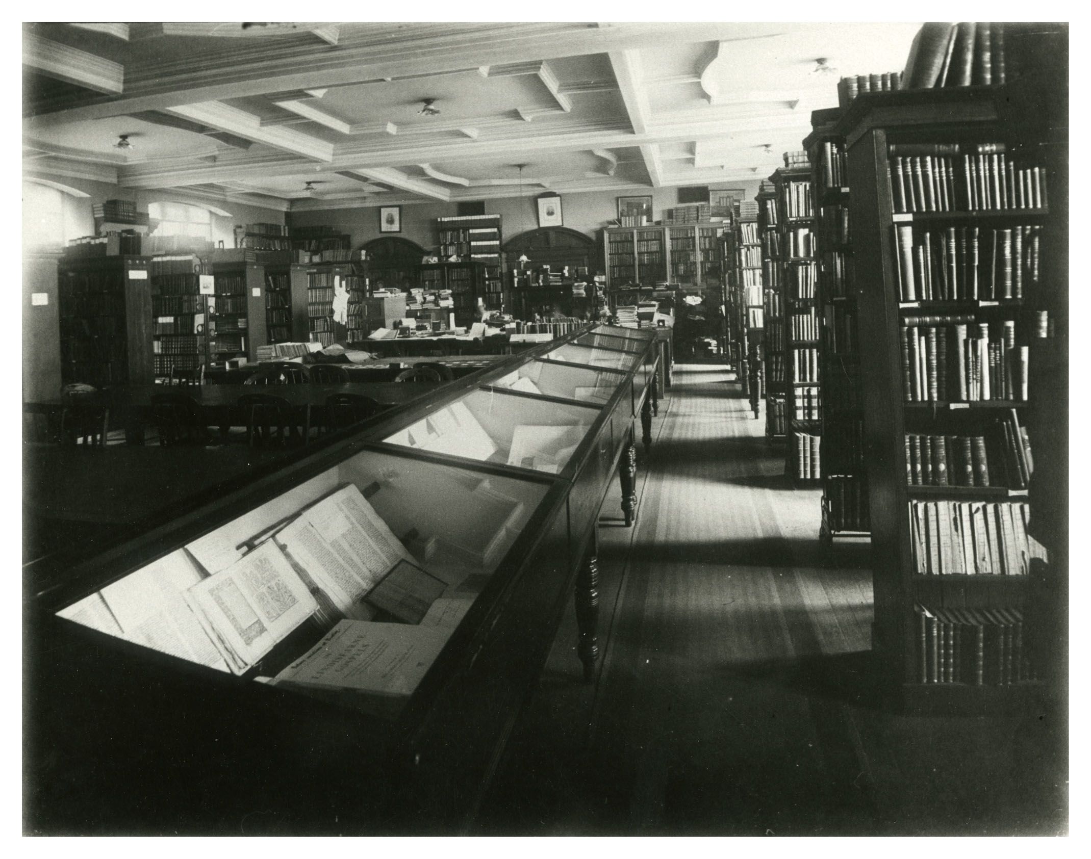 Photograph of the Armstrong Library with wooden bookcases and glass exhibition display cabinets. 