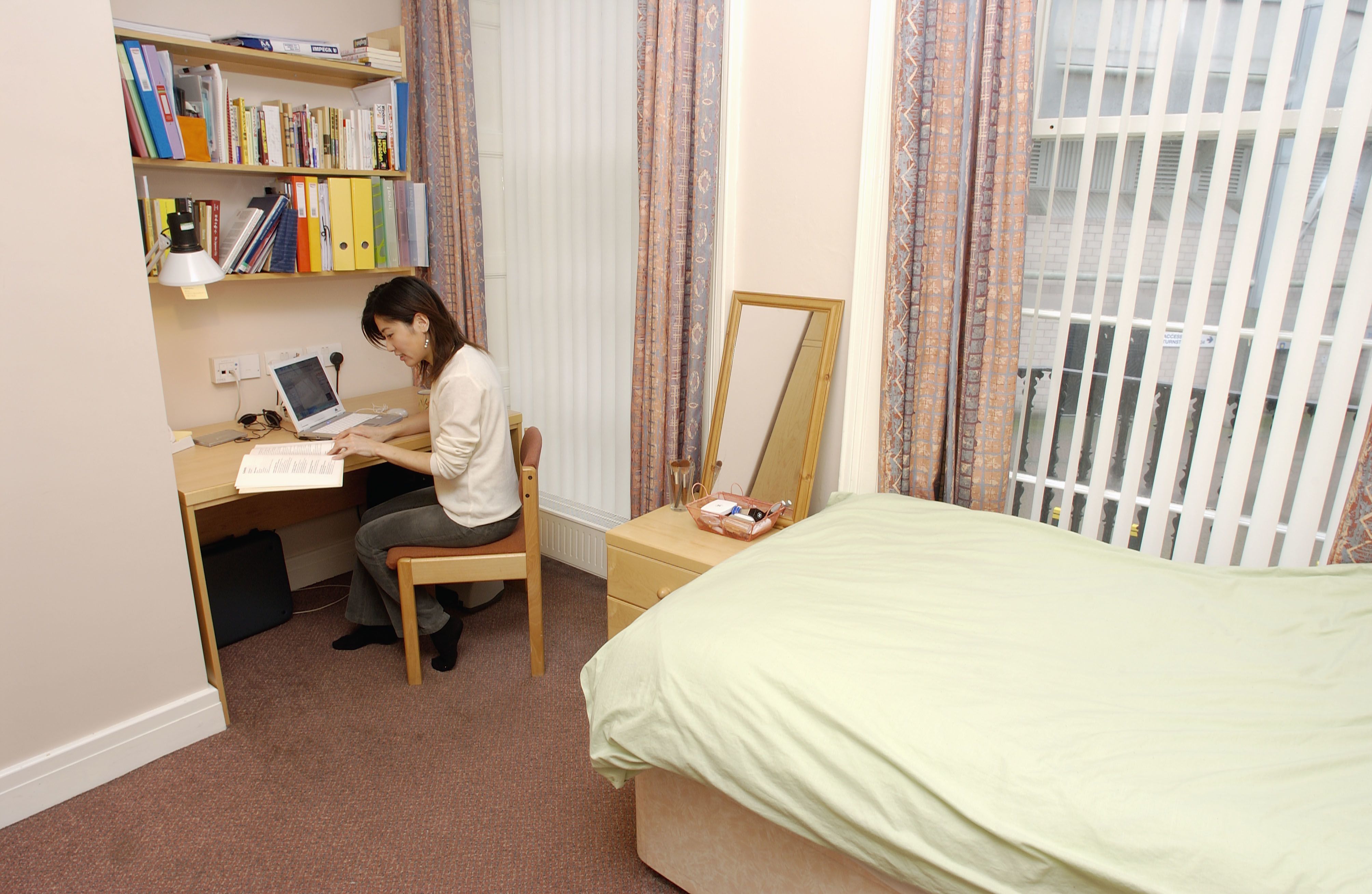 Photograph of a student studying in her bedroom, 2004.