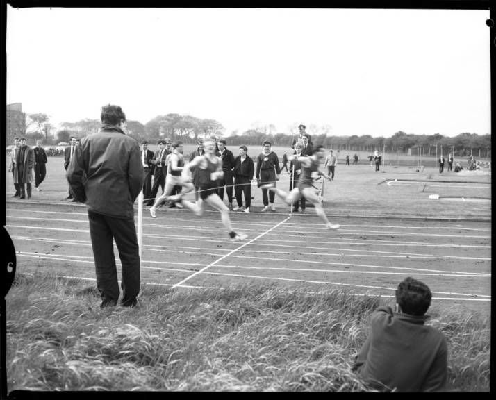 Photograph of student crossing the finishing line from running a race during a sports meeting at Cochrane Park, 1964. NUA/K/032968/05