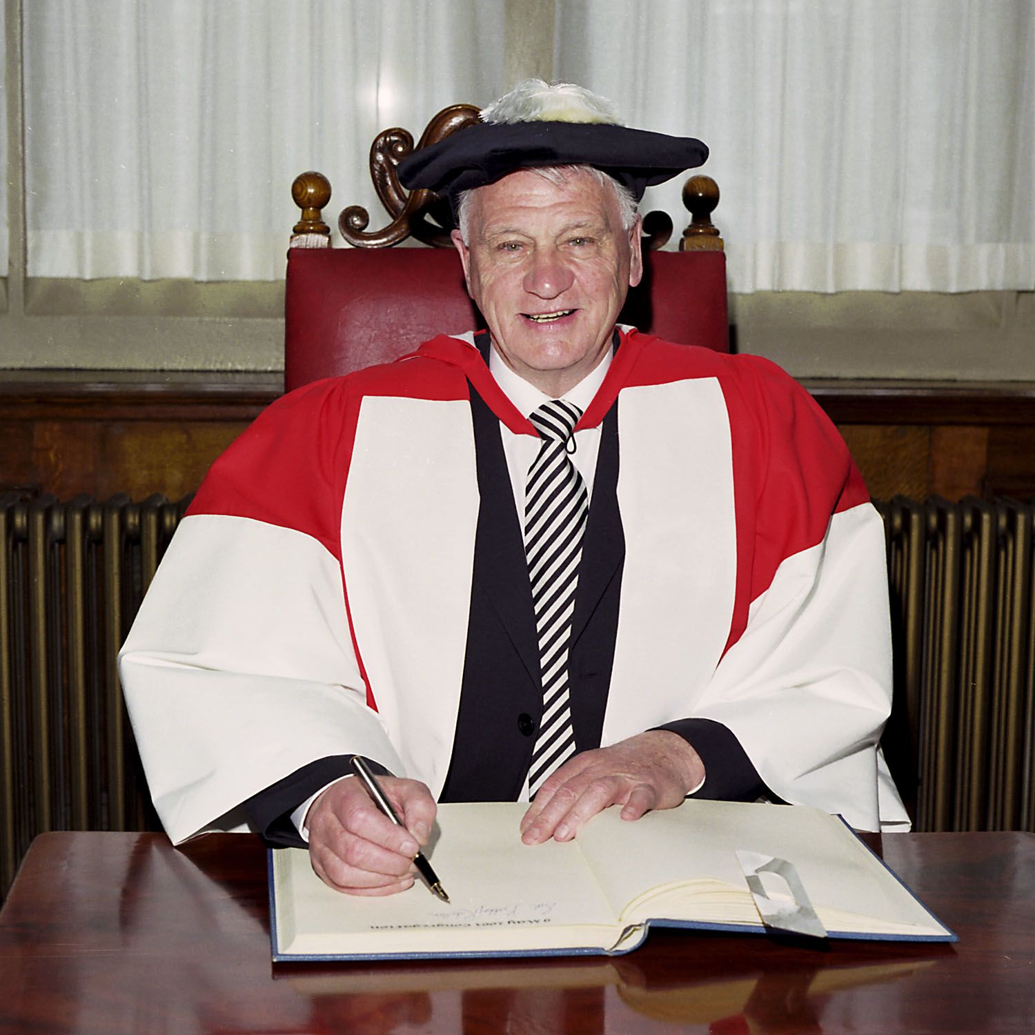 Photograph of Sir Bobby Robson signing the book when receiving an honorary degree, 2003. NUA/308755/02.
