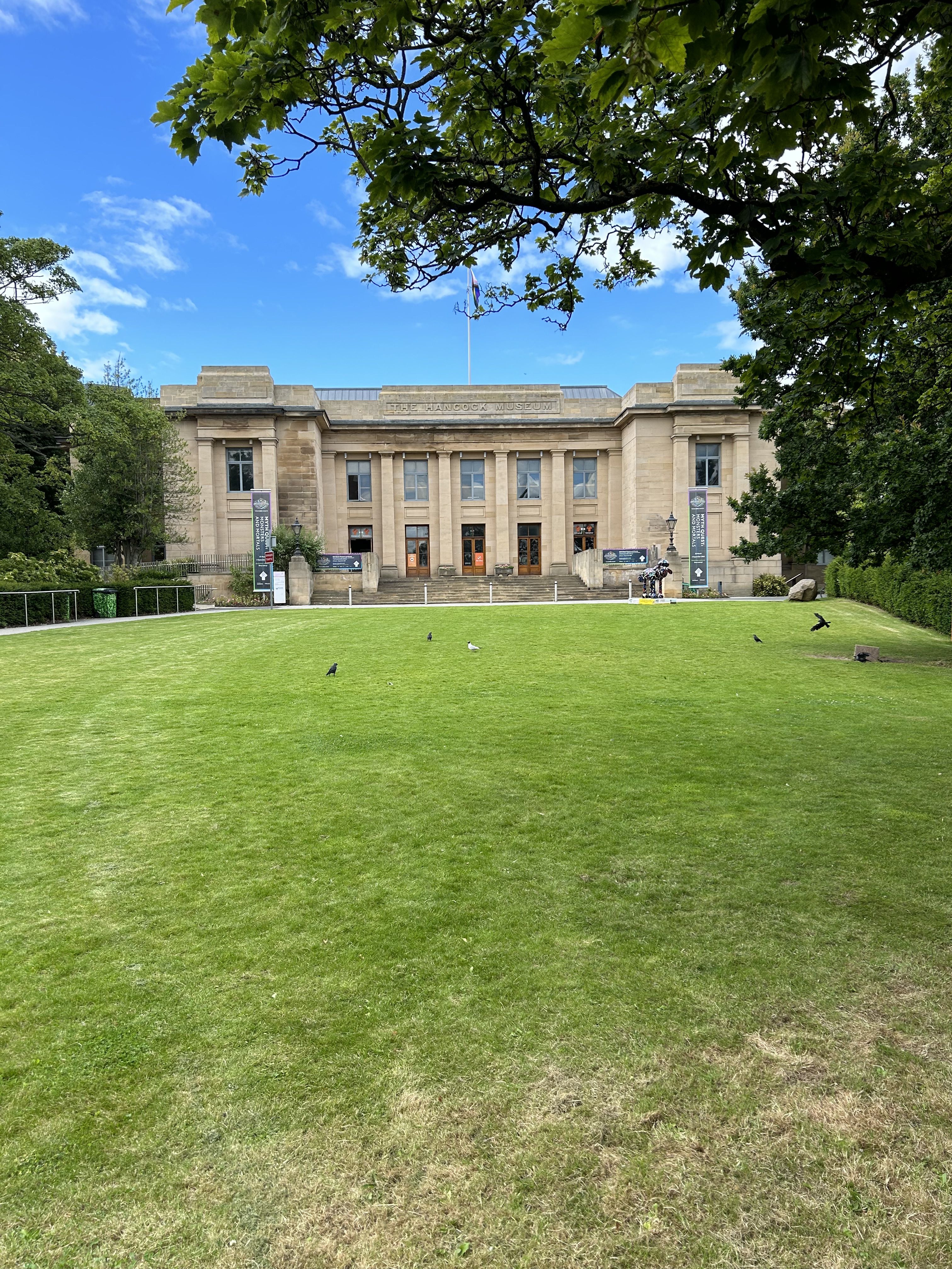 A large lawn with trees and a building with a flag on it.