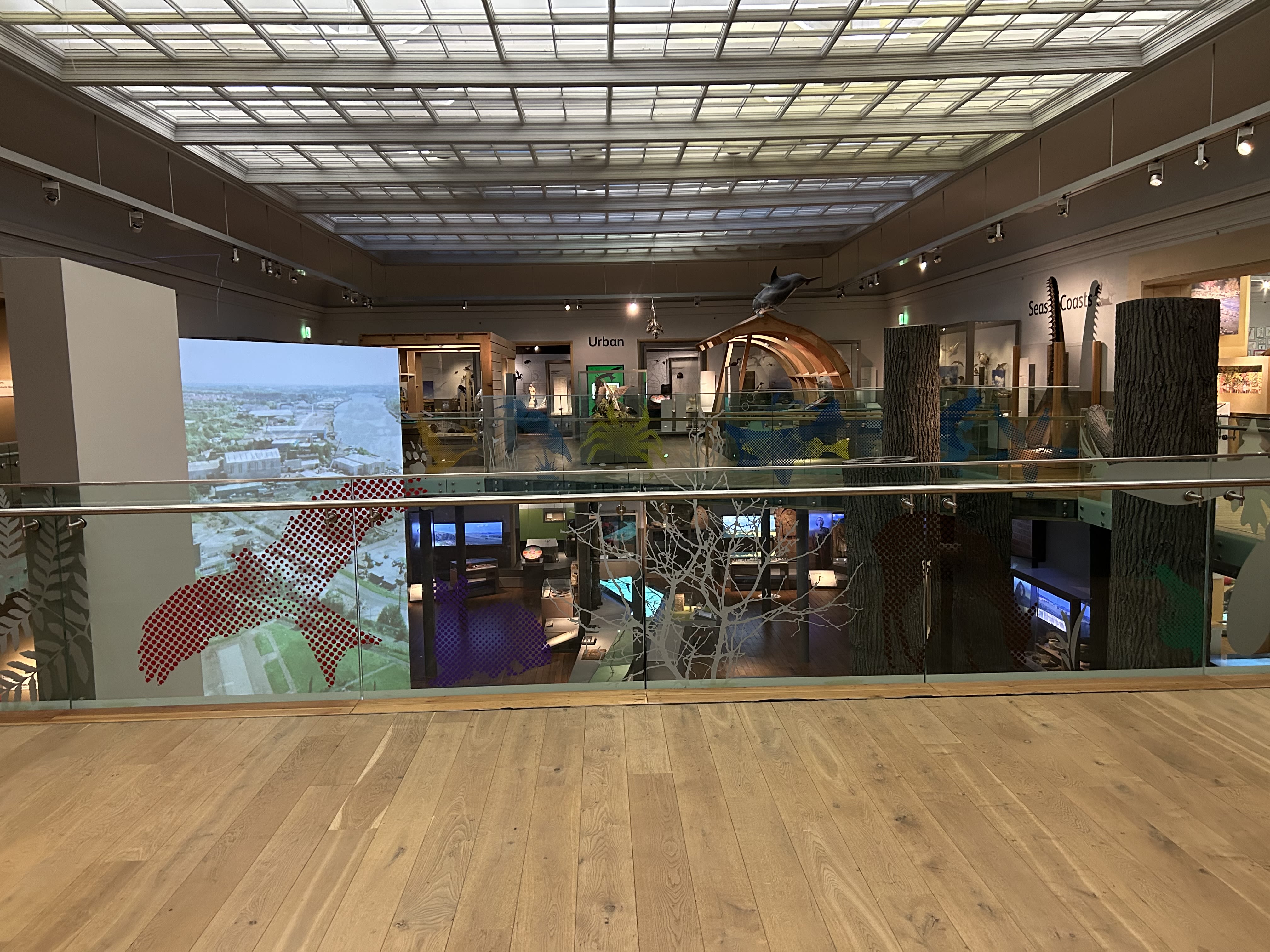 Two levels of galleries with wood floors and glass railings. 